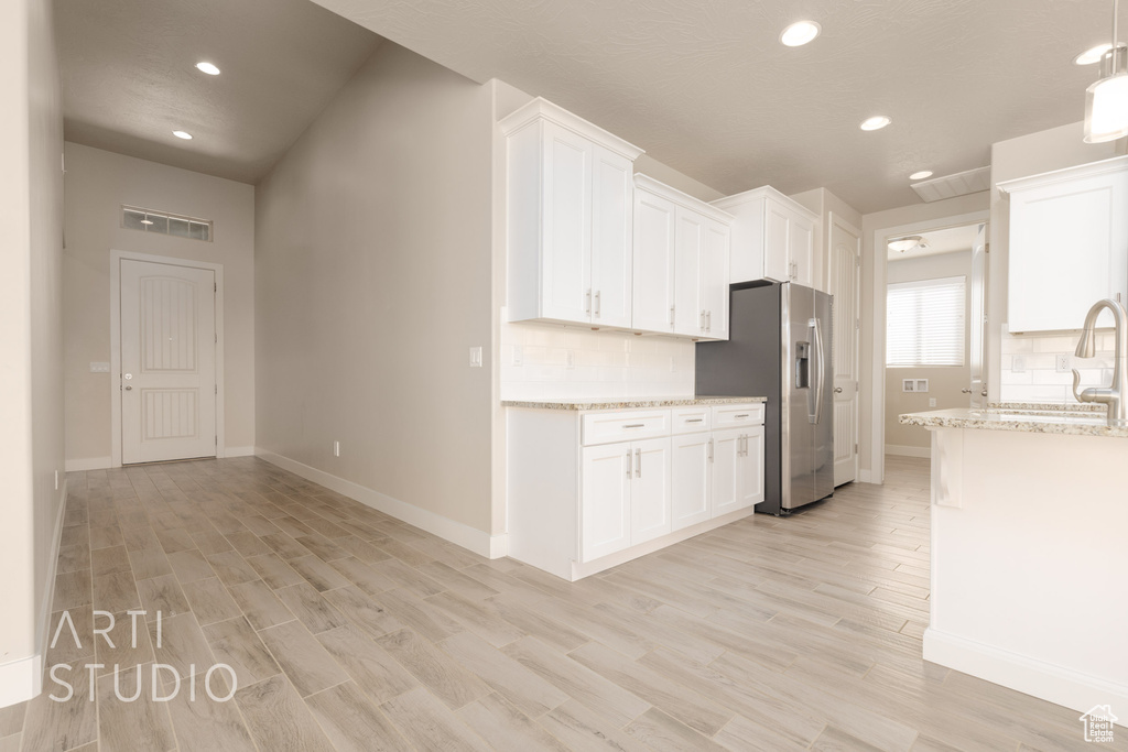 Kitchen featuring light stone counters, white cabinets, and light hardwood / wood-style floors