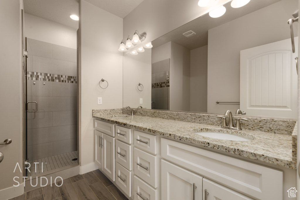 Bathroom featuring hardwood / wood-style floors, a shower with door, and vanity