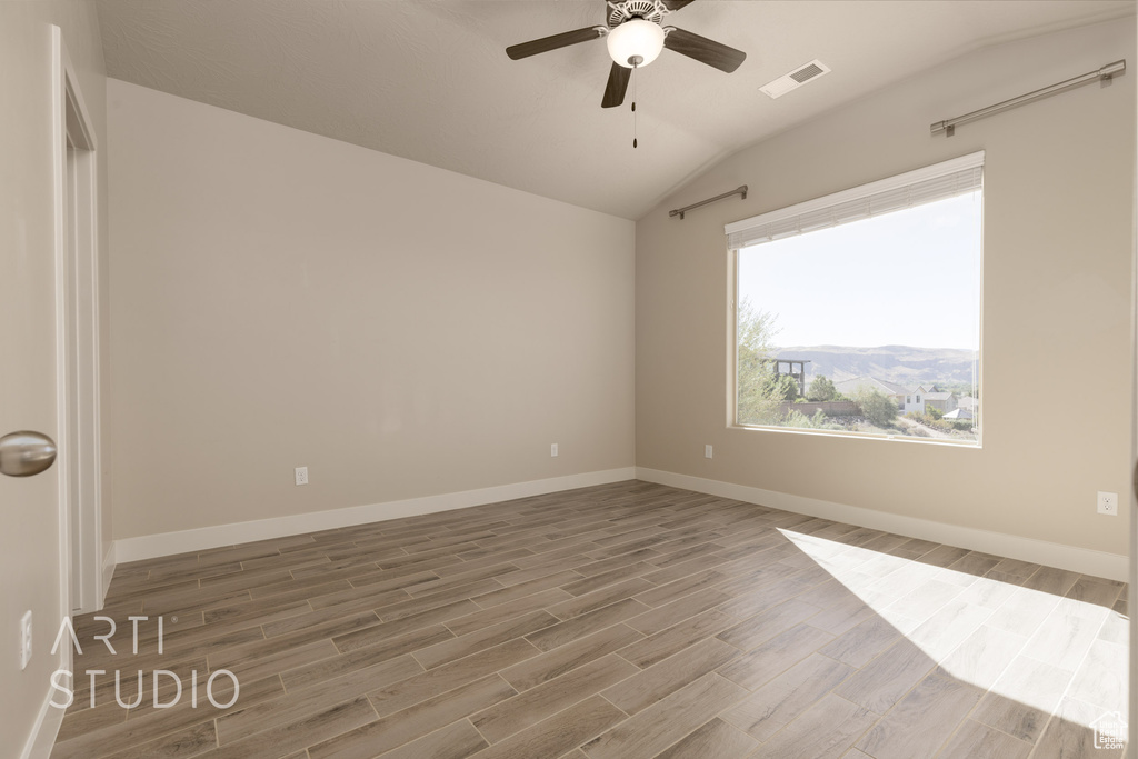 Empty room with vaulted ceiling, ceiling fan, and hardwood / wood-style floors