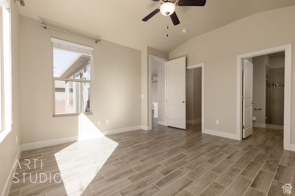 Unfurnished bedroom with hardwood / wood-style floors, lofted ceiling, ensuite bath, and ceiling fan