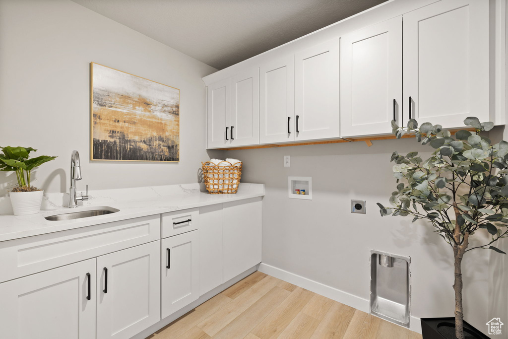 Washroom featuring washer hookup, sink, cabinets, light wood-type flooring, and electric dryer hookup