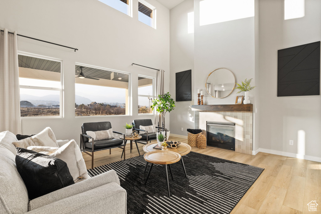 Living room with a towering ceiling, a tiled fireplace, and light hardwood / wood-style flooring