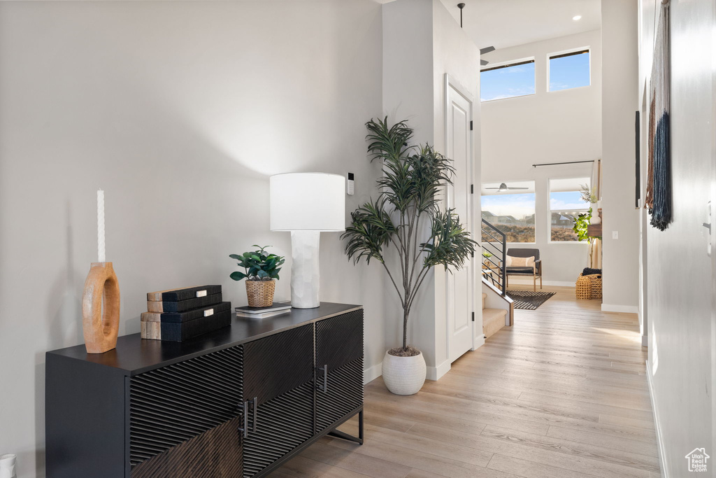 Hall featuring light hardwood / wood-style flooring and a towering ceiling