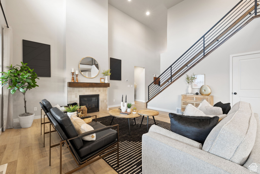 Living room with a fireplace, a high ceiling, and light hardwood / wood-style flooring