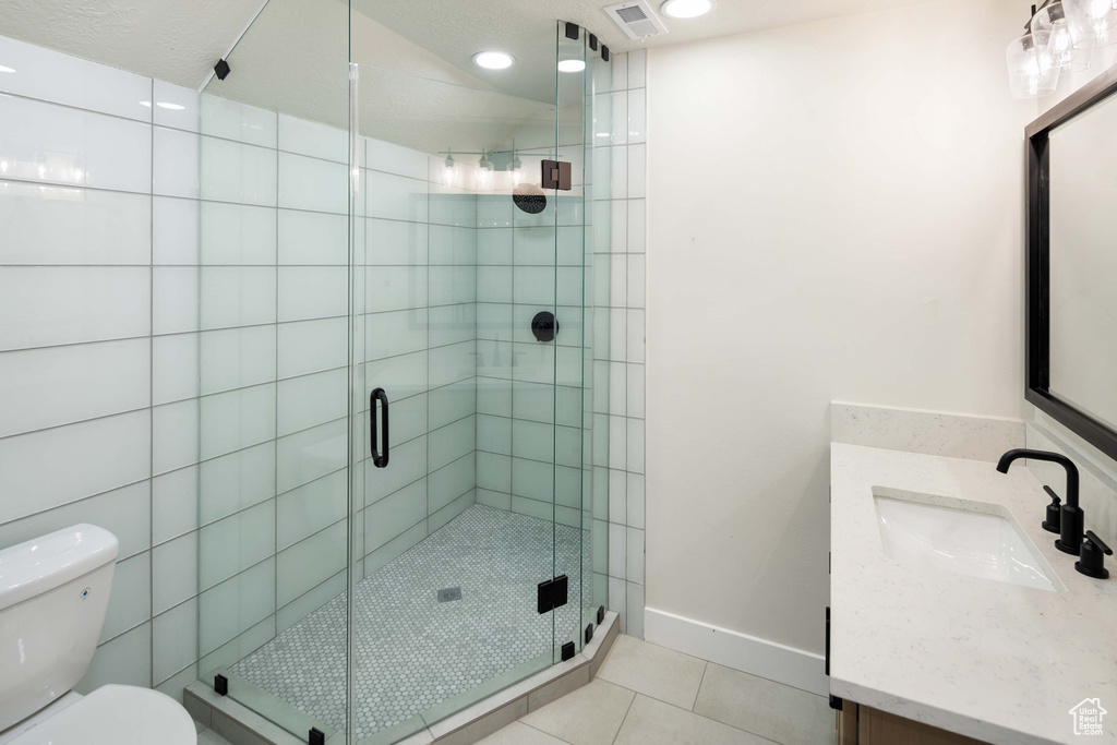 Bathroom with walk in shower, tile patterned flooring, vanity, and toilet