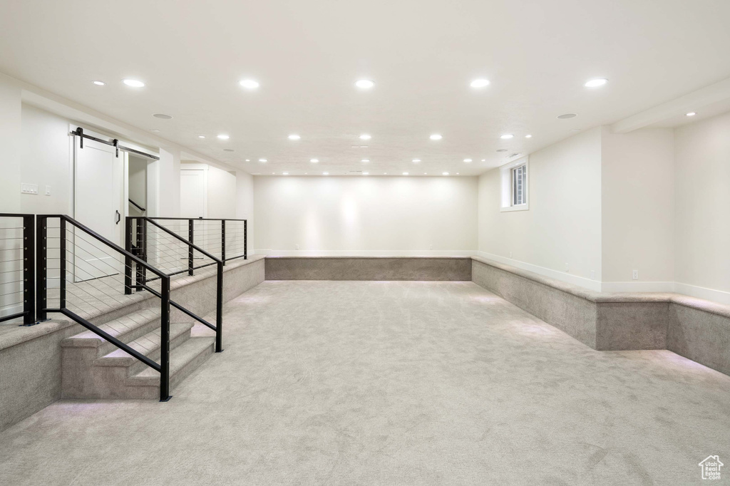 Basement featuring light colored carpet and a barn door