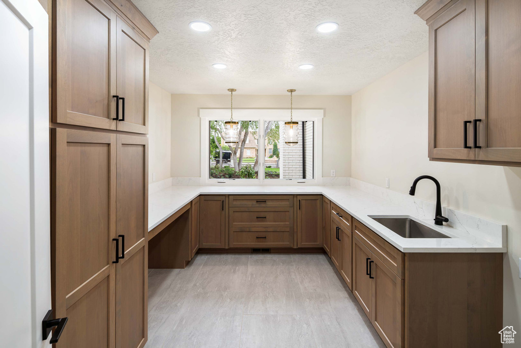 Kitchen featuring sink, hanging light fixtures, kitchen peninsula, and a textured ceiling