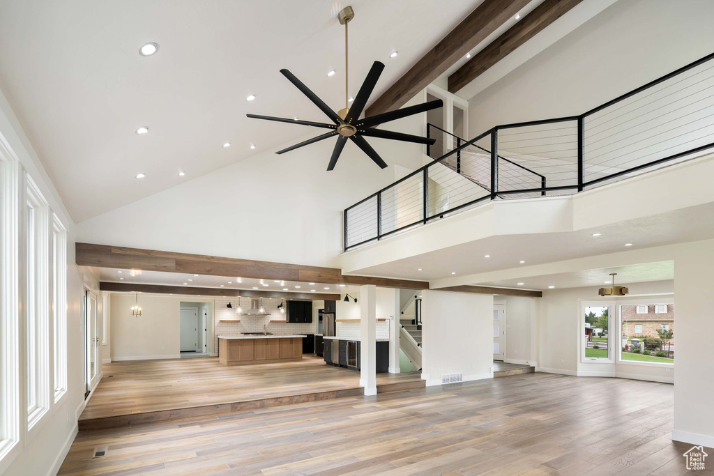 Unfurnished living room featuring light hardwood / wood-style flooring, beam ceiling, and high vaulted ceiling