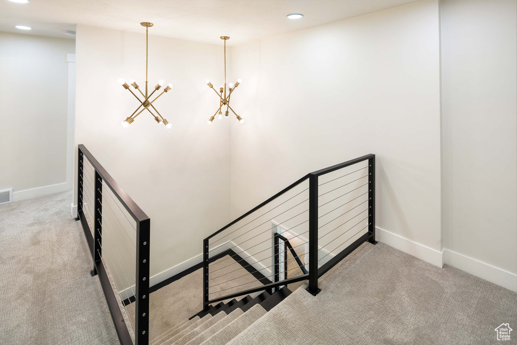 Stairway featuring carpet floors and a notable chandelier