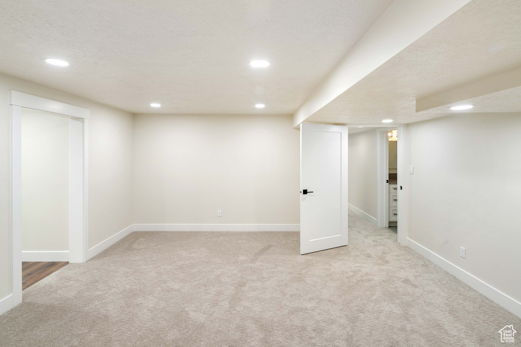 Basement featuring light carpet and a textured ceiling