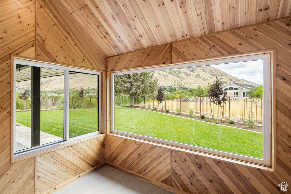 Unfurnished sunroom featuring wooden ceiling, vaulted ceiling, and a mountain view