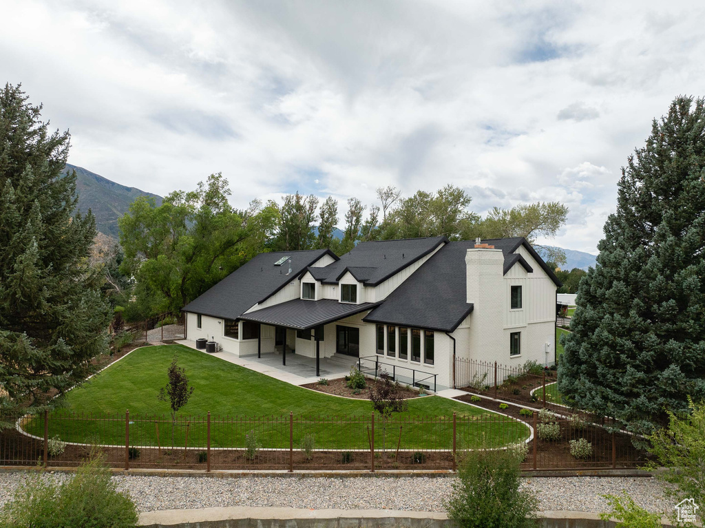 Back of property featuring a mountain view and a lawn