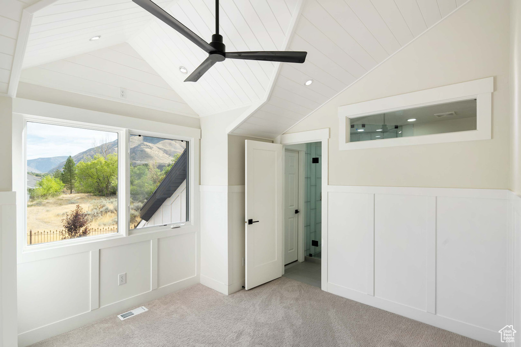 Unfurnished bedroom featuring lofted ceiling, ceiling fan, light colored carpet, and a mountain view