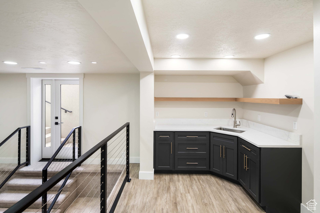 Bar featuring a textured ceiling, sink, and light hardwood / wood-style flooring