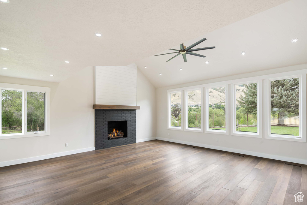 Unfurnished living room featuring a fireplace, a textured ceiling, wood-type flooring, lofted ceiling, and ceiling fan