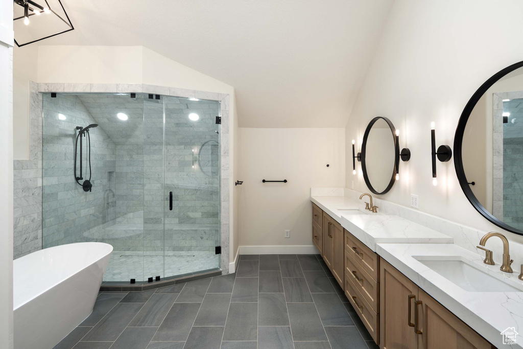 Bathroom featuring lofted ceiling, vanity, and separate shower and tub