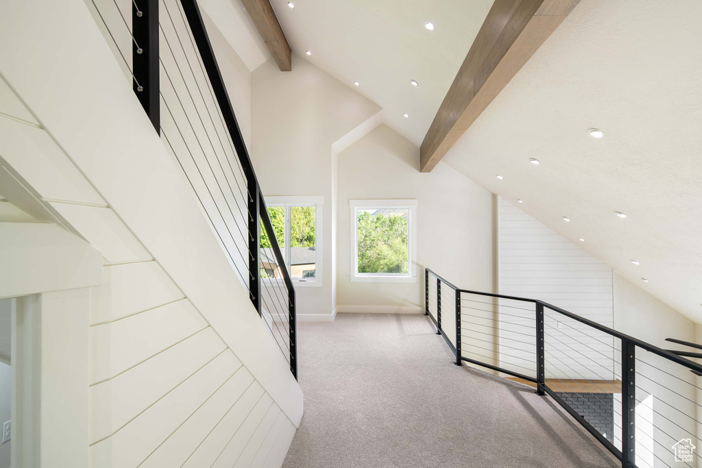 Hall featuring beamed ceiling, light colored carpet, and high vaulted ceiling