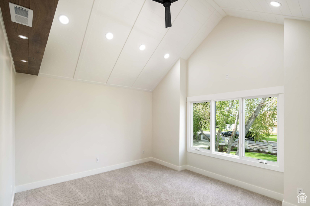 Carpeted spare room featuring lofted ceiling