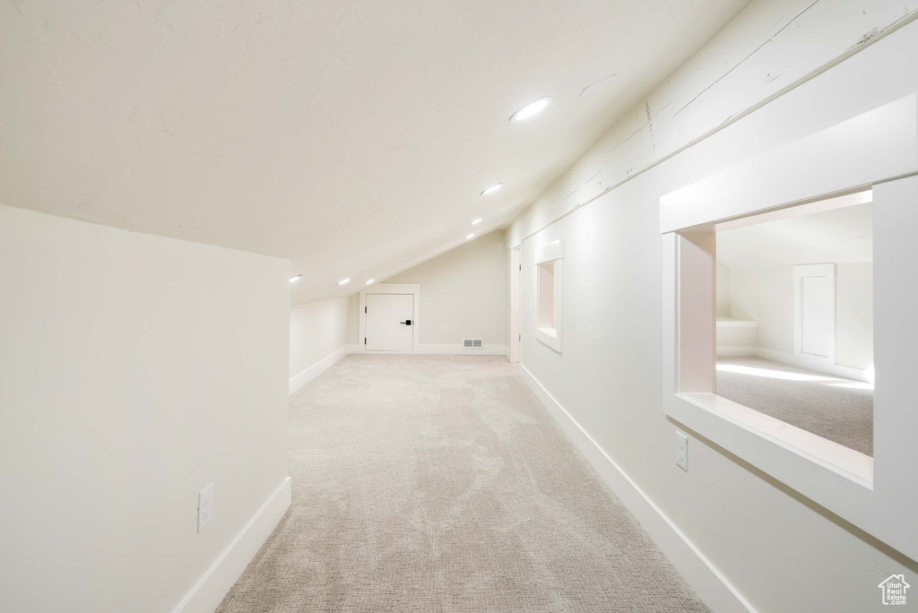 Additional living space with lofted ceiling and light colored carpet