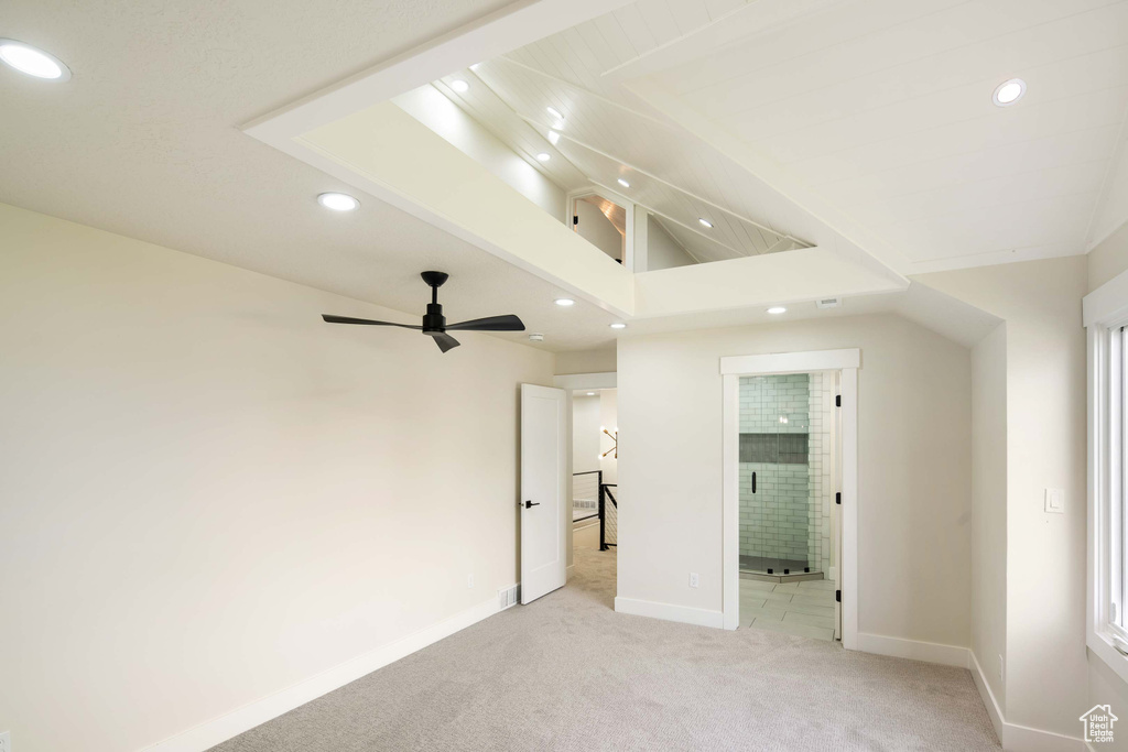 Unfurnished bedroom featuring connected bathroom, lofted ceiling, ceiling fan, and light colored carpet