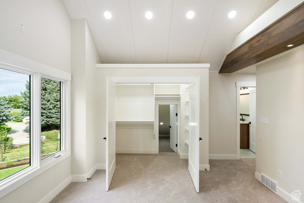 Unfurnished bedroom with vaulted ceiling and light colored carpet