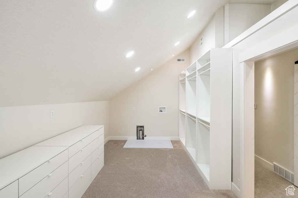 Bonus room with a textured ceiling, vaulted ceiling, and light carpet