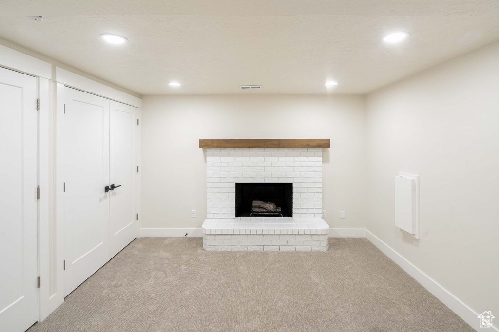 Unfurnished living room with light carpet and a fireplace