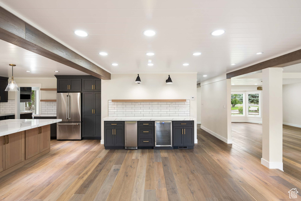 Kitchen featuring stainless steel fridge, beverage cooler, light hardwood / wood-style flooring, and decorative light fixtures