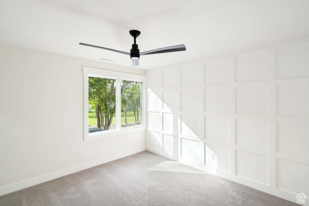 Empty room with ceiling fan and light carpet