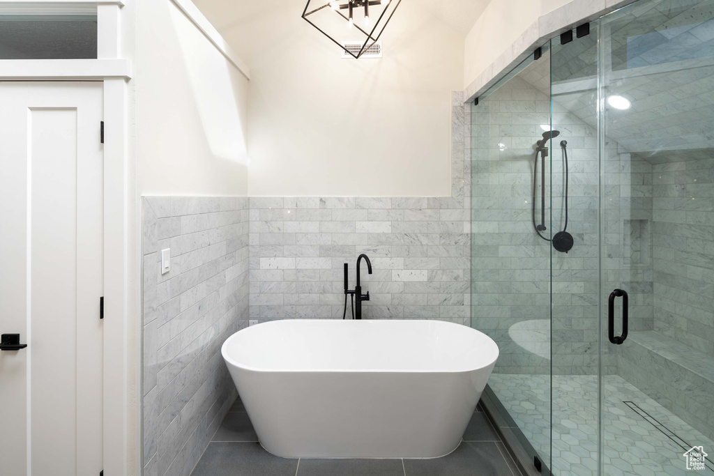 Bathroom featuring tile walls, tile patterned floors, and shower with separate bathtub