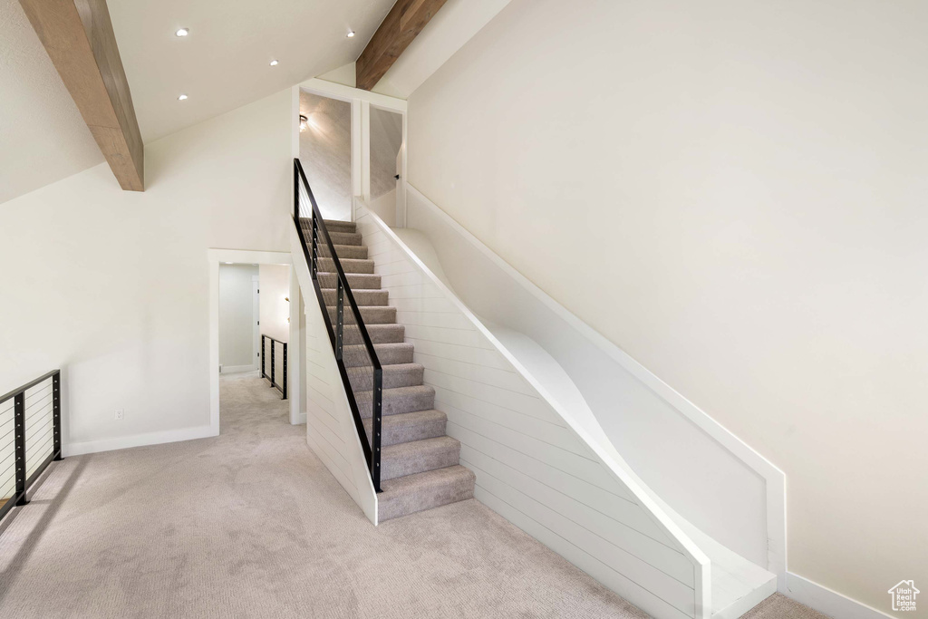 Stairs featuring beam ceiling, carpet, and high vaulted ceiling