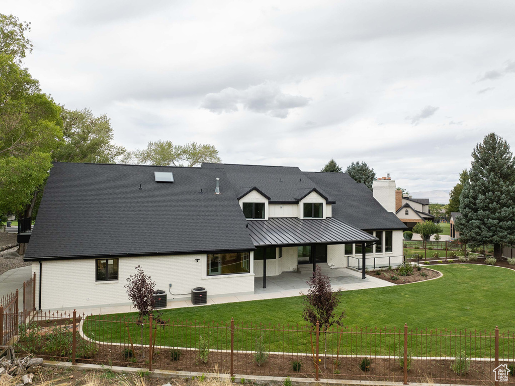 Rear view of property featuring a yard, a patio, and central air condition unit