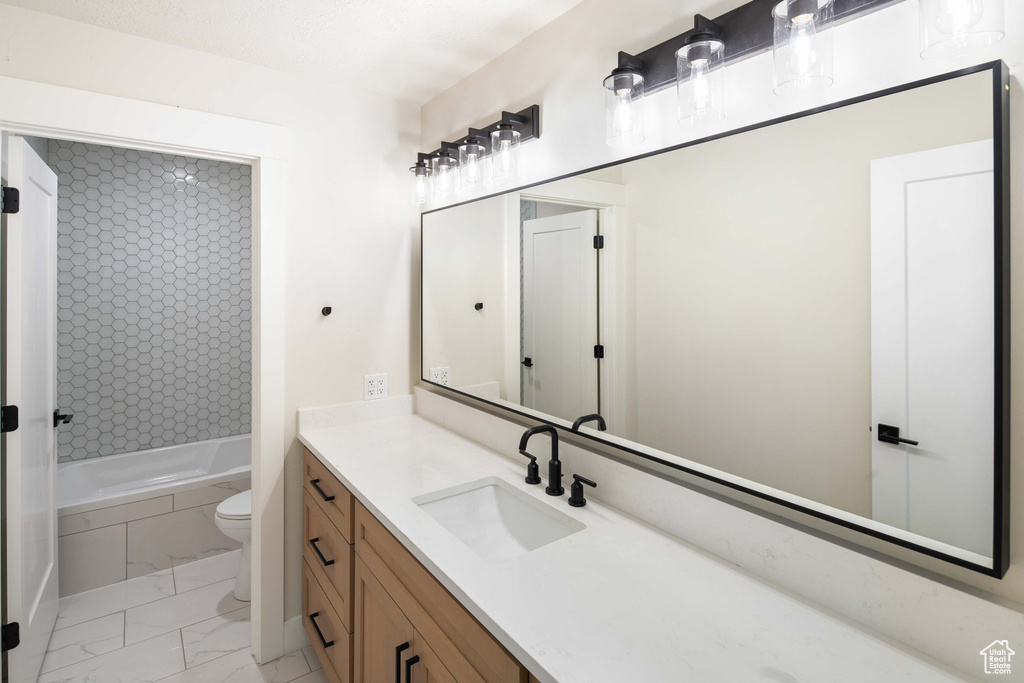 Full bathroom featuring tiled shower / bath, vanity, and toilet