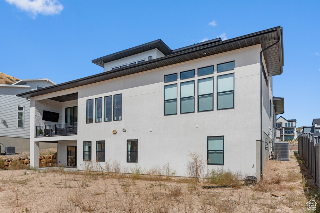 Rear view of house featuring a balcony and central air condition unit