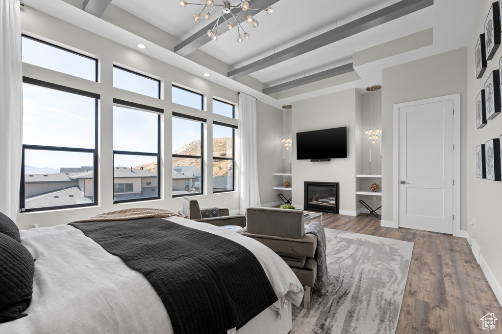 Bedroom featuring light hardwood / wood-style floors, beam ceiling, and a notable chandelier