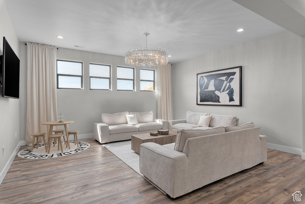 Living room with an inviting chandelier, hardwood / wood-style floors, and a healthy amount of sunlight