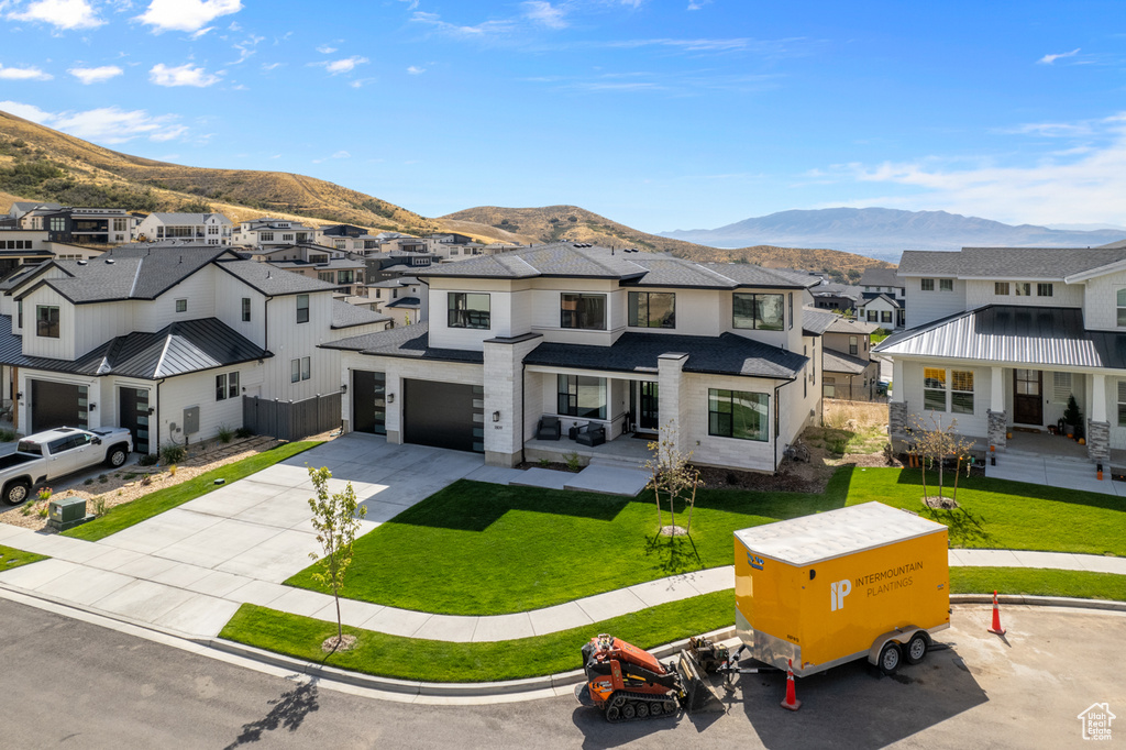 View of front of house with a garage, a front lawn, and a mountain view