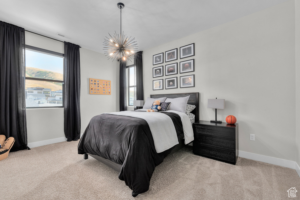 Bedroom with an inviting chandelier and light colored carpet