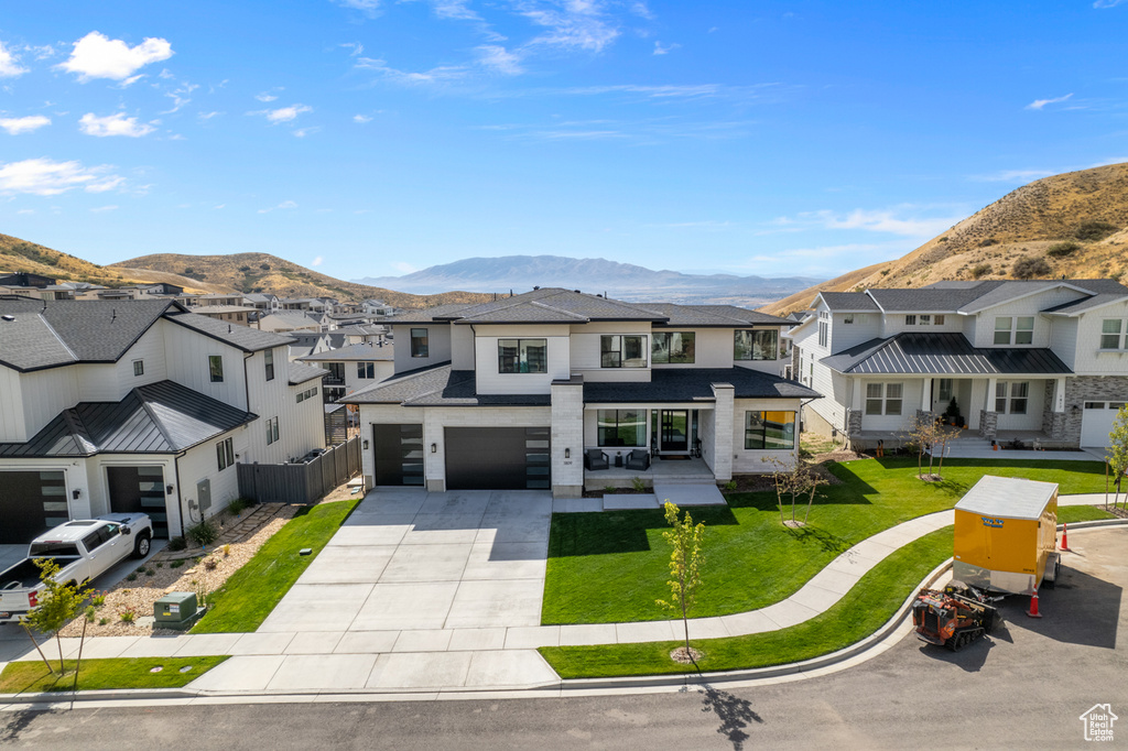 View of front facade with a mountain view, a front lawn, and a garage