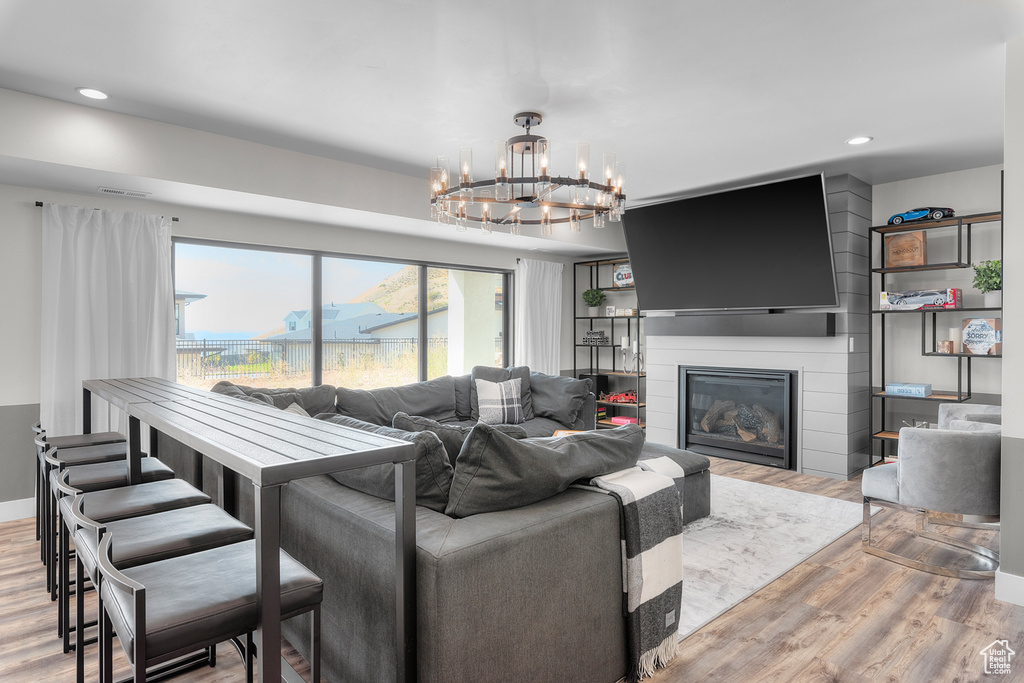 Living room with an inviting chandelier, light hardwood / wood-style flooring, and a fireplace