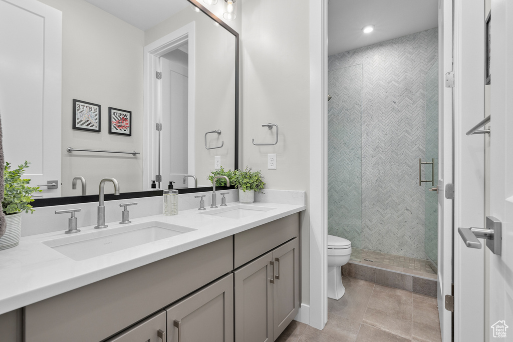 Bathroom with tiled shower, vanity, toilet, and tile patterned floors