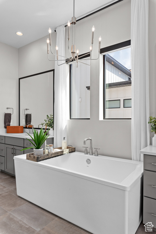 Bathroom featuring a notable chandelier, a tub to relax in, tile patterned flooring, and vanity