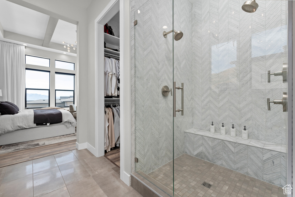 Bathroom with beam ceiling, tile patterned flooring, and a shower with door