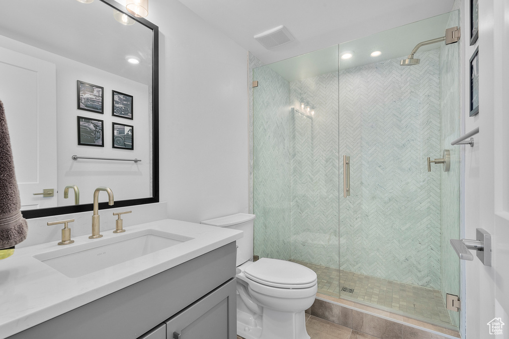 Bathroom featuring tile patterned flooring, vanity, toilet, and an enclosed shower