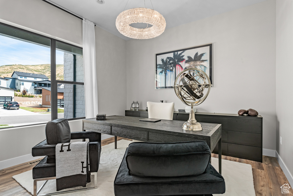 Home office featuring wood-type flooring and an inviting chandelier