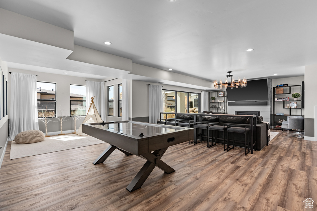 Game room featuring hardwood / wood-style flooring, a notable chandelier, and a large fireplace