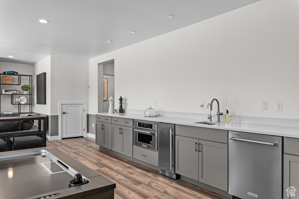 Kitchen featuring gray cabinets, appliances with stainless steel finishes, hardwood / wood-style floors, and sink