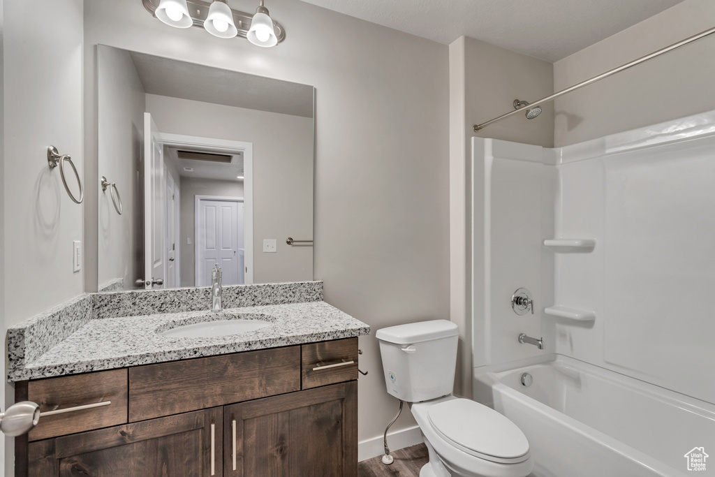 Full bathroom with shower / bathing tub combination, vanity, hardwood / wood-style floors, and toilet