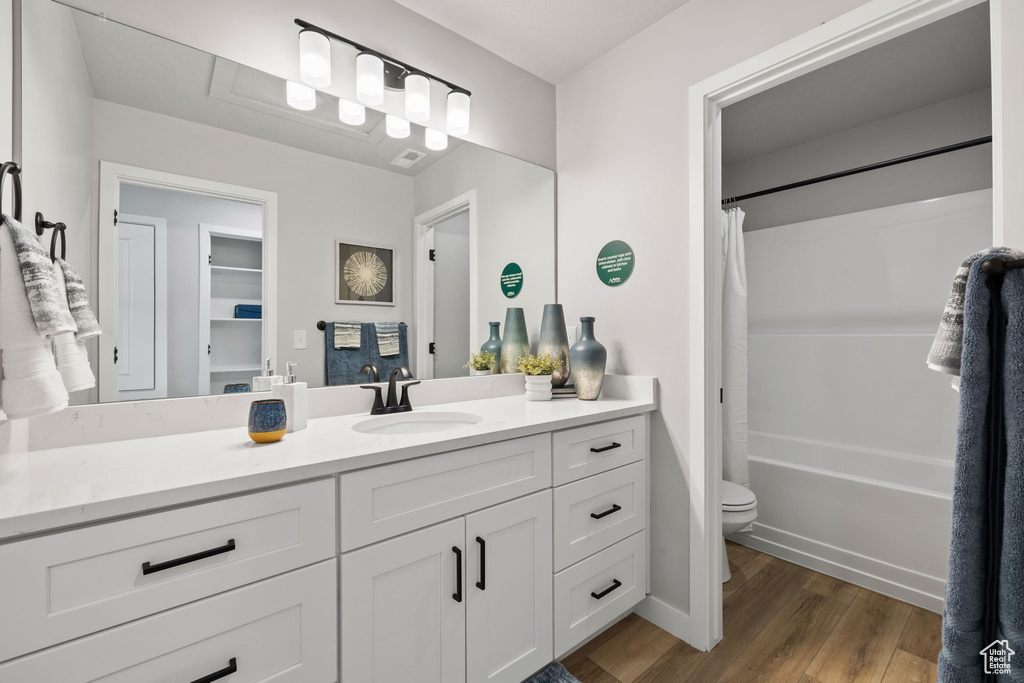 Full bathroom with shower / tub combo, wood-type flooring, vanity, and toilet