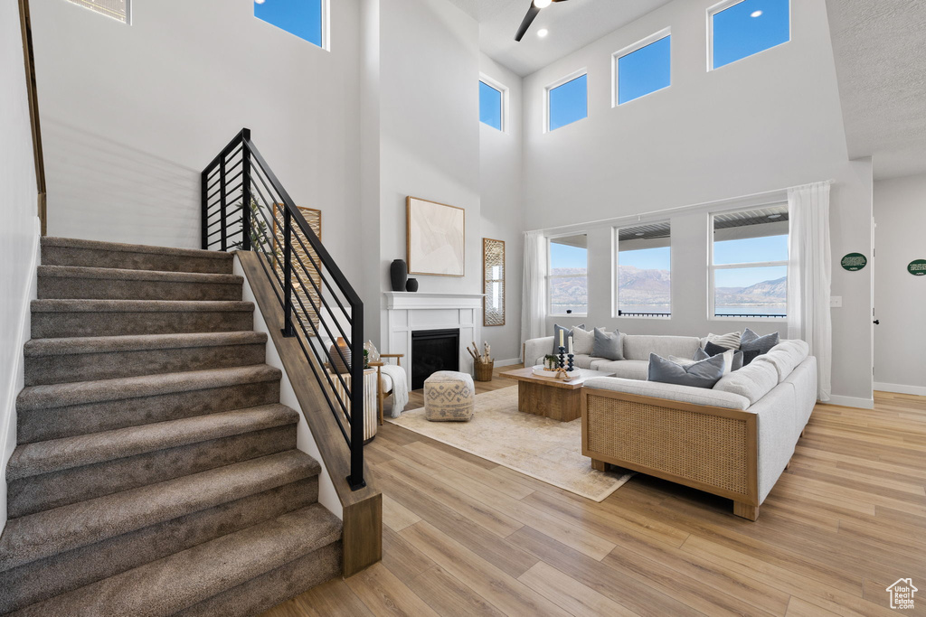 Living room with a textured ceiling, light hardwood / wood-style flooring, and a towering ceiling